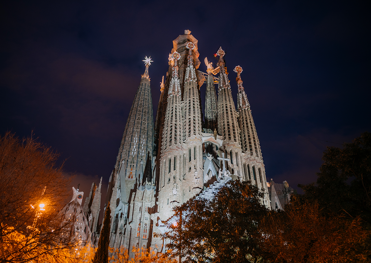 Sagrada Familia illuminated facade at night from a wide exterior viewpoint in Barcelona